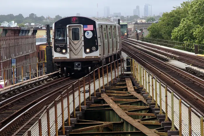 An image of the F train outside, with the NYC skyline behind